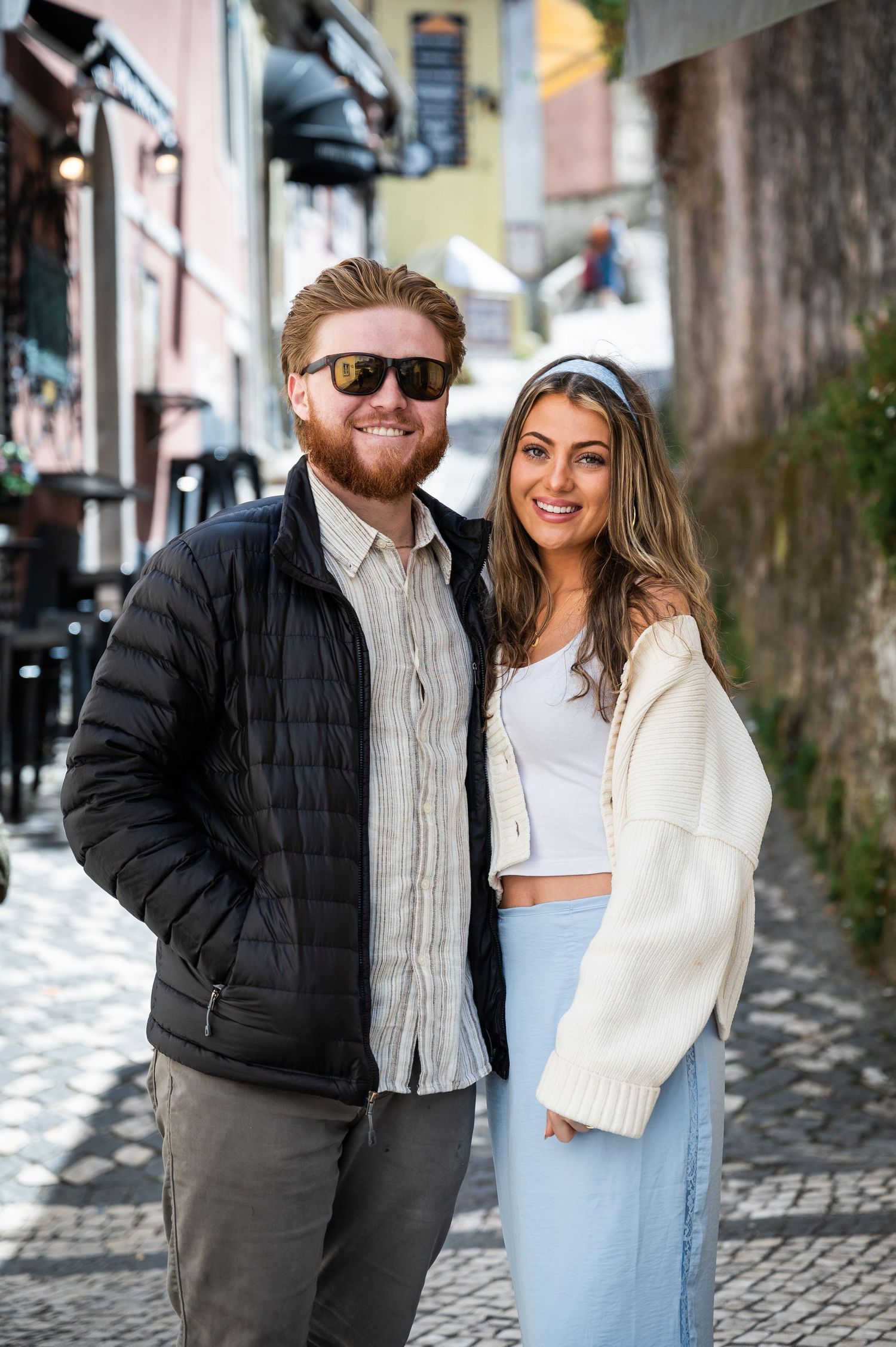 Happy couple posing together on a charming cobblestone street in a European old town.