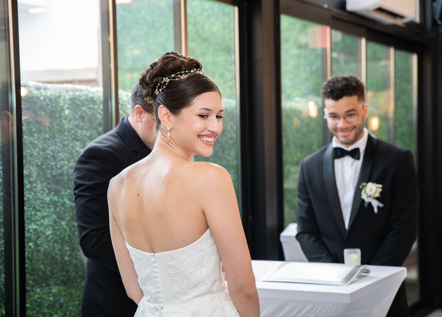 The bride is looking over her shoulder and smiling during the ceremony in Bayonne, NJ