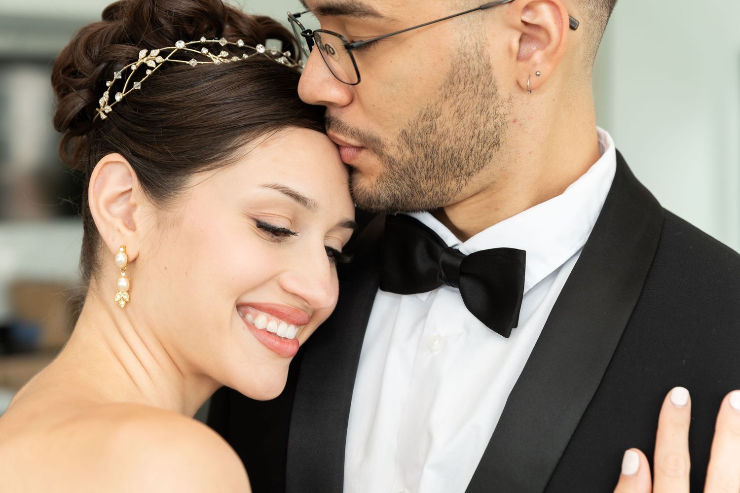 A photo of the bride and groom on their wedding day while the groom kisses the bride's forehead as she smiles in Bayonne, NJ