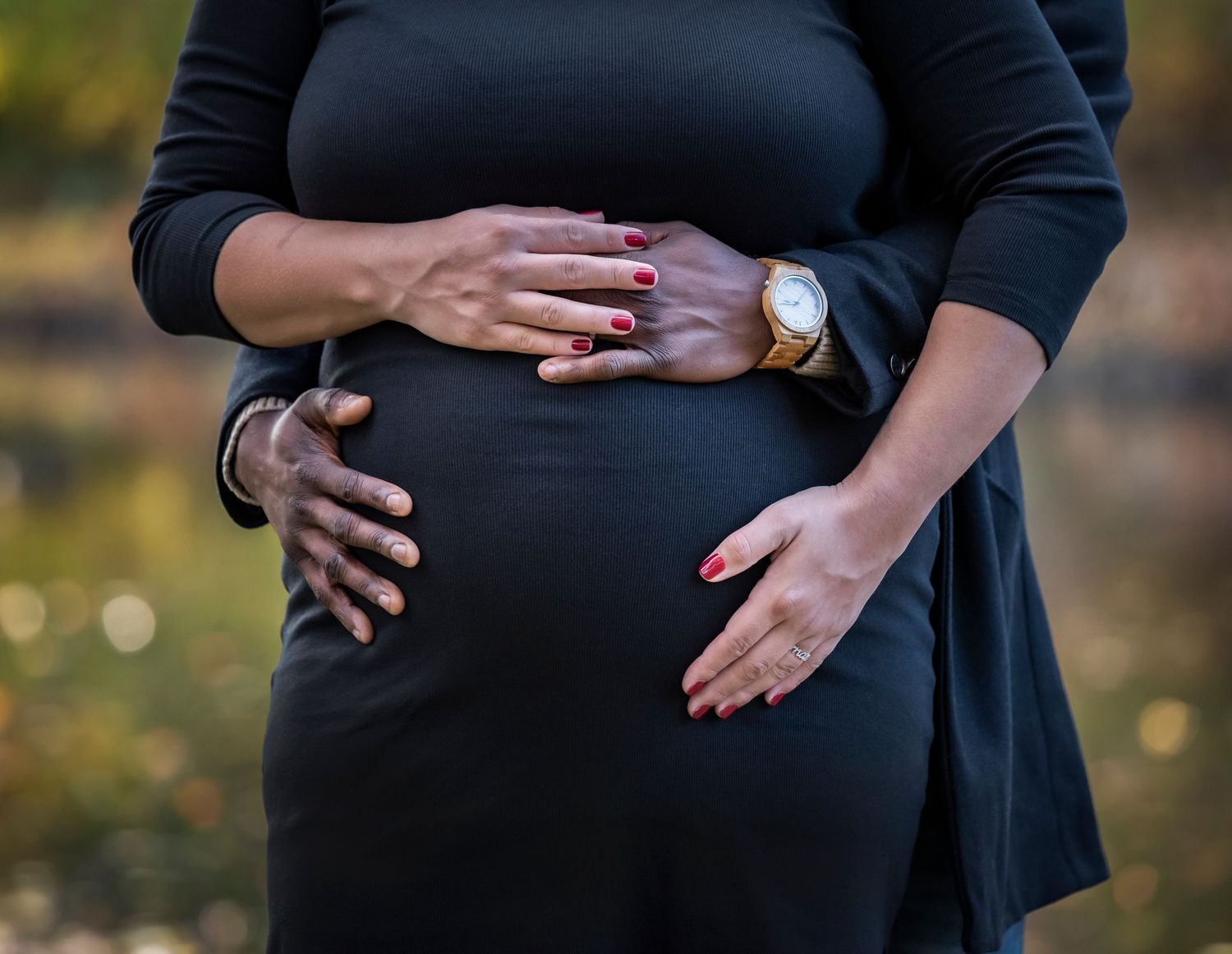 A couple during their maternity photoshoot and the husband is holding the mom's belly and their fingers are intertwined in Nutley, NJ