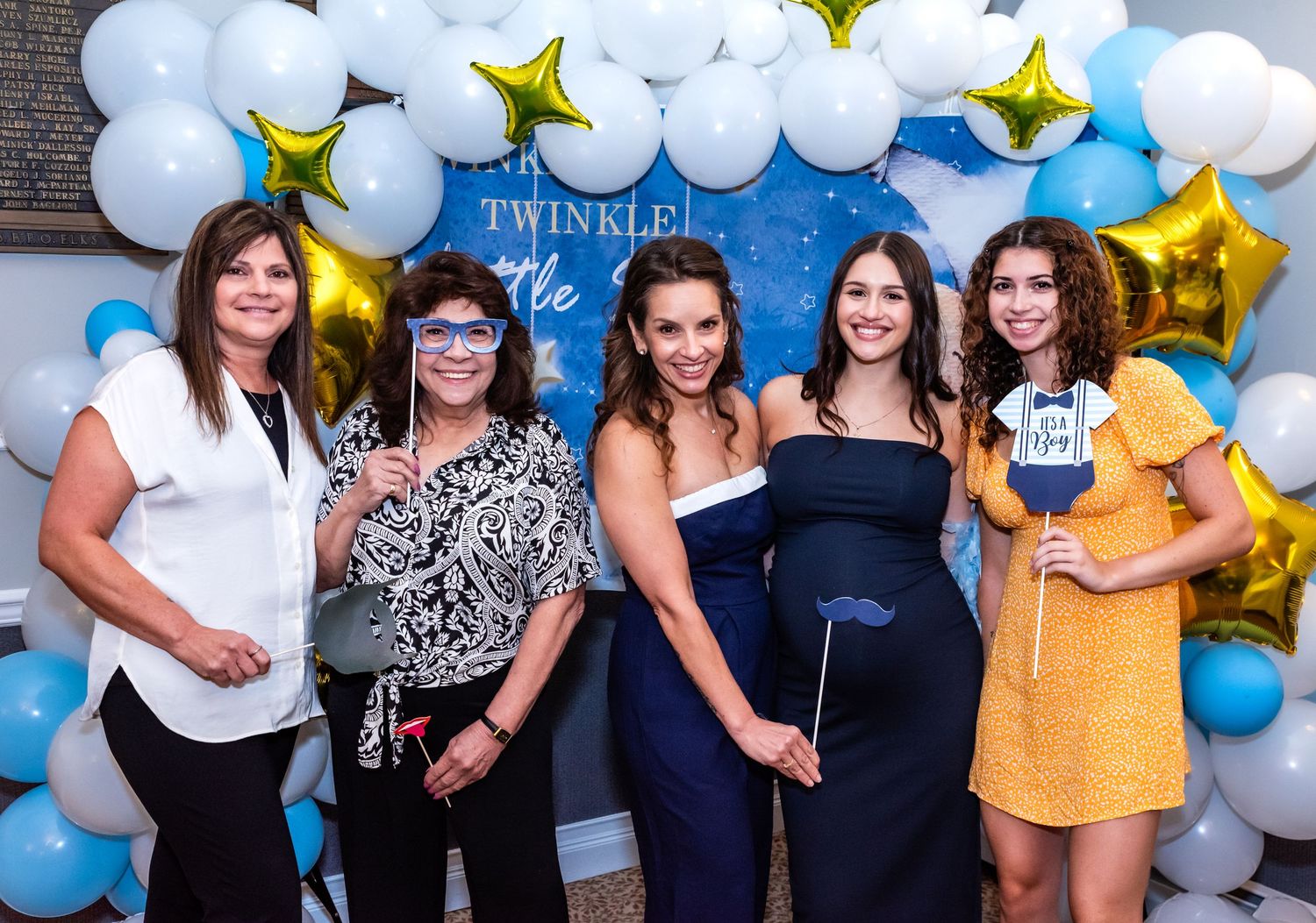 Five women celebrating a baby shower in Bridgewater, NJ, laughing and posing with funny photo props