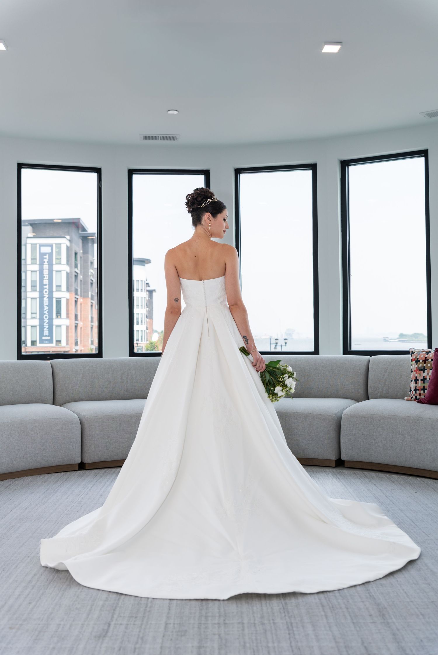 A full body shot of the back of the bride in her wedding dress as she looks off to the side in Bayonne, NJ