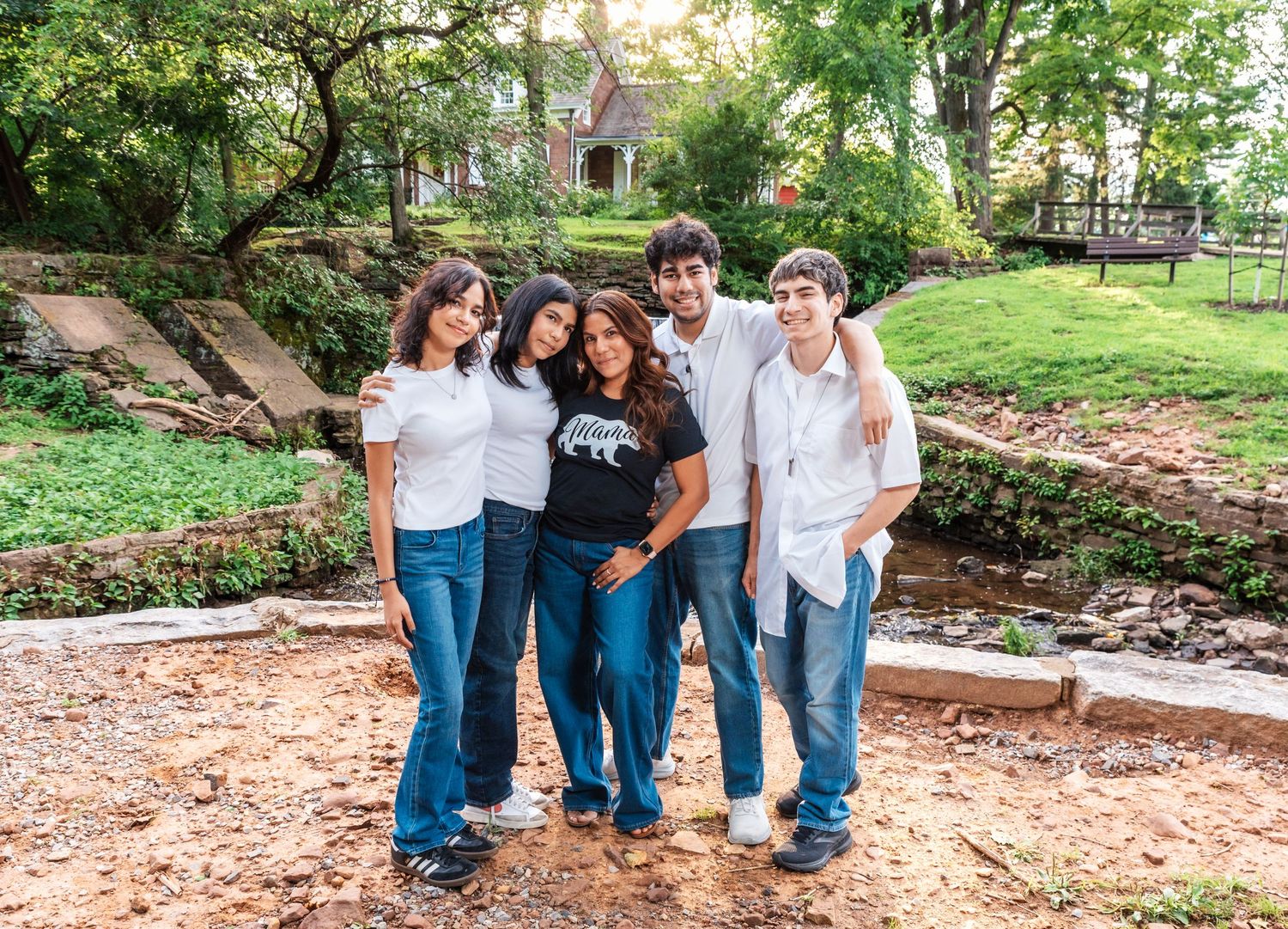 A mom with her 4 kids stands together, and smiles during their family photo session in Nutley, NJ