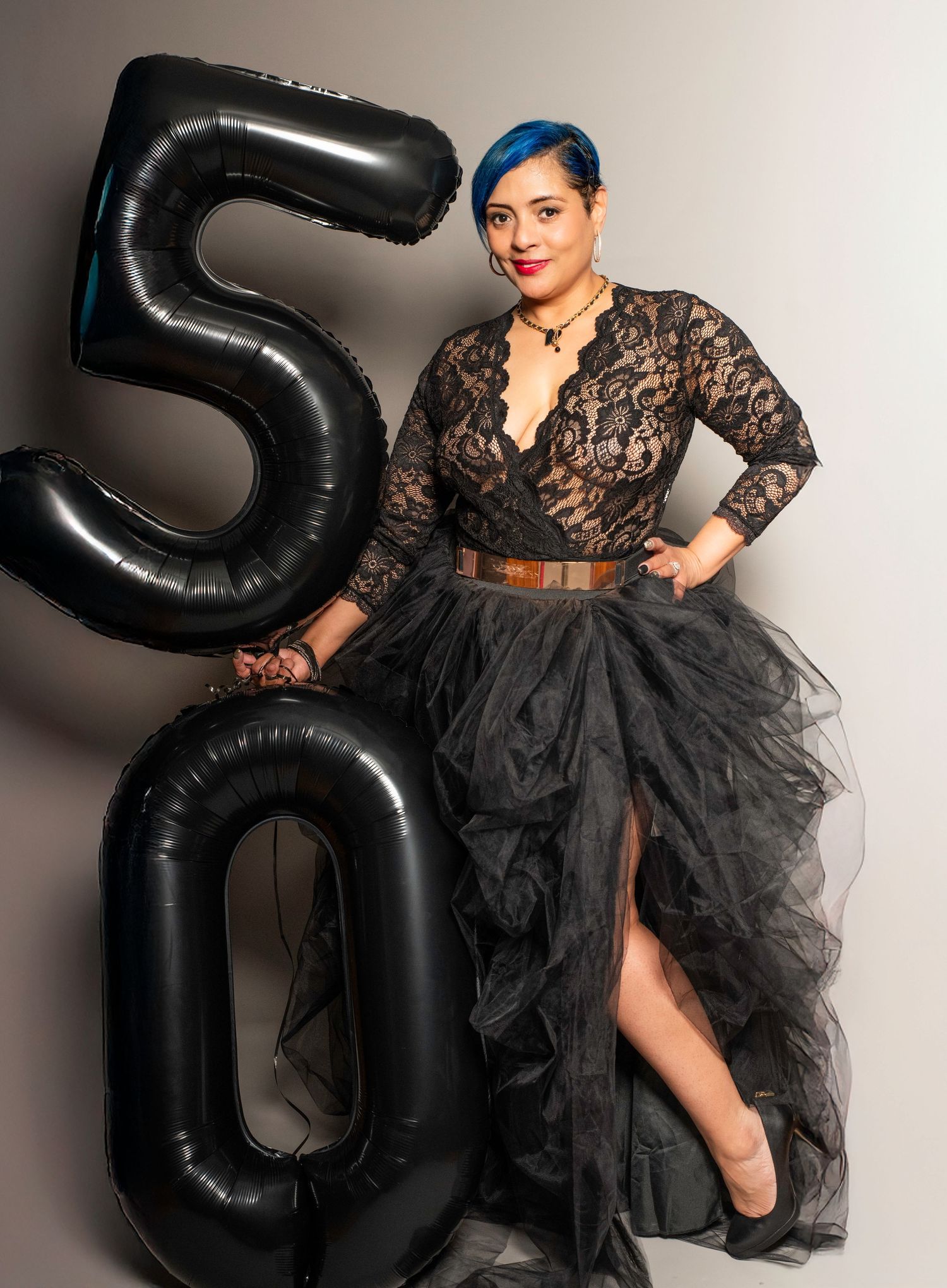 A portrait of a woman standing and holding ballons that say 50 for her 50th birthday photo shoot in Woodridge, NJ