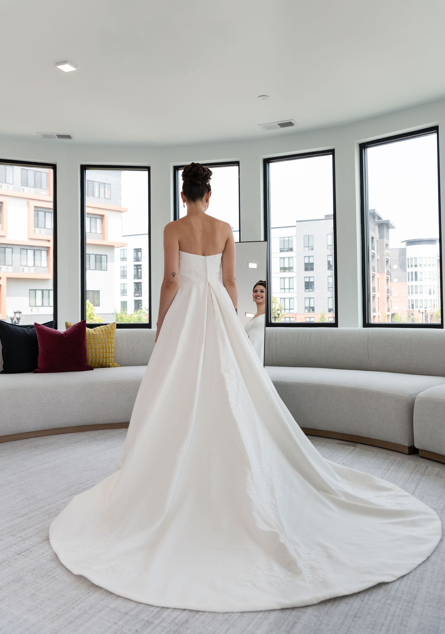 A full body shot of the back of the bride in her wedding dress as she looks into the mirror in Bayonne, NJ