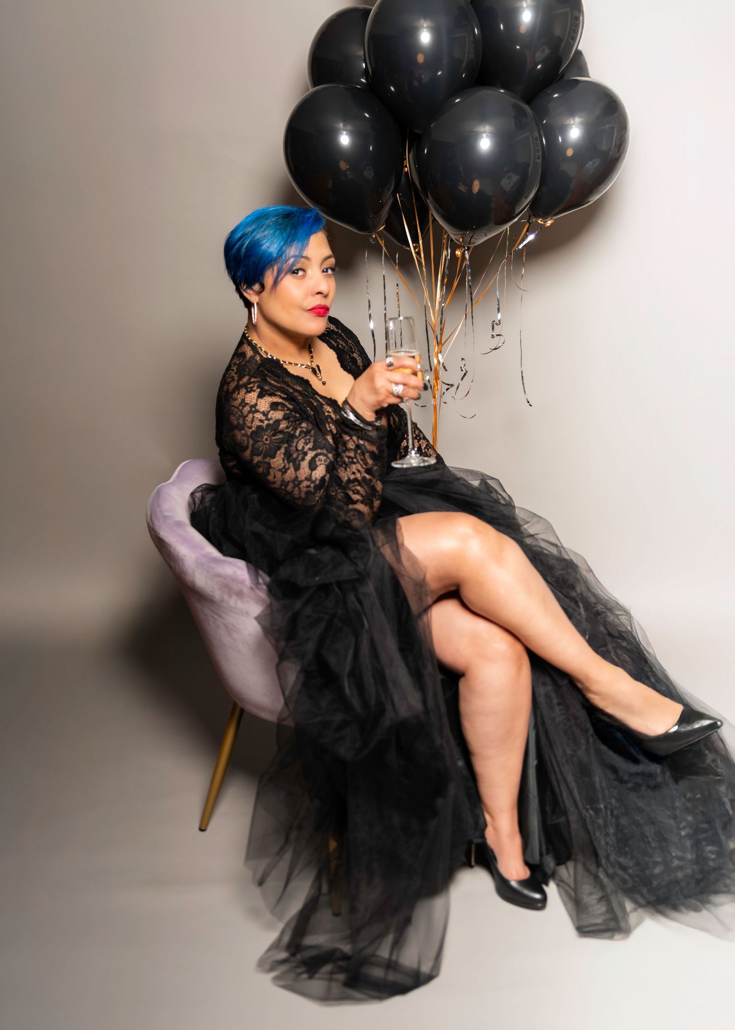 A portrait of a woman for a 50th birthday photo shoot in her home holding a glass of champagne with balloons in Woodridge, NJ