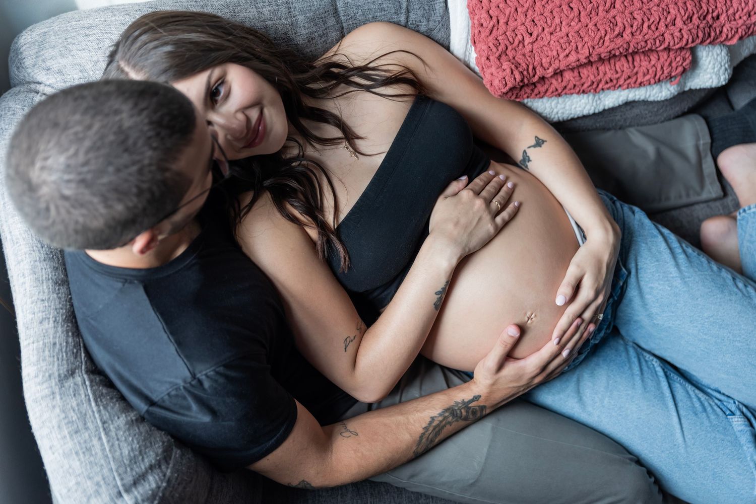 A couple during their maternity photoshoot has their hands intertwined with each other's over the mother's belly in Edgewater, NJ