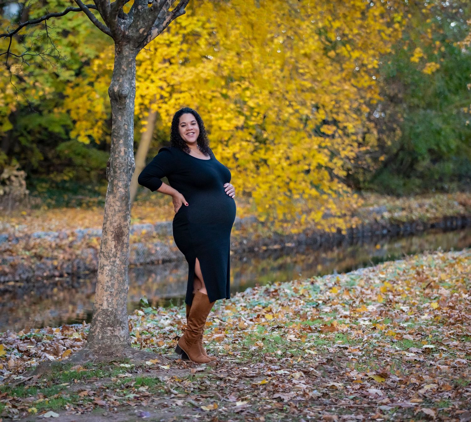 A woman at her maternity shoot in a park during autumn holding her belly in Nutley, NJ