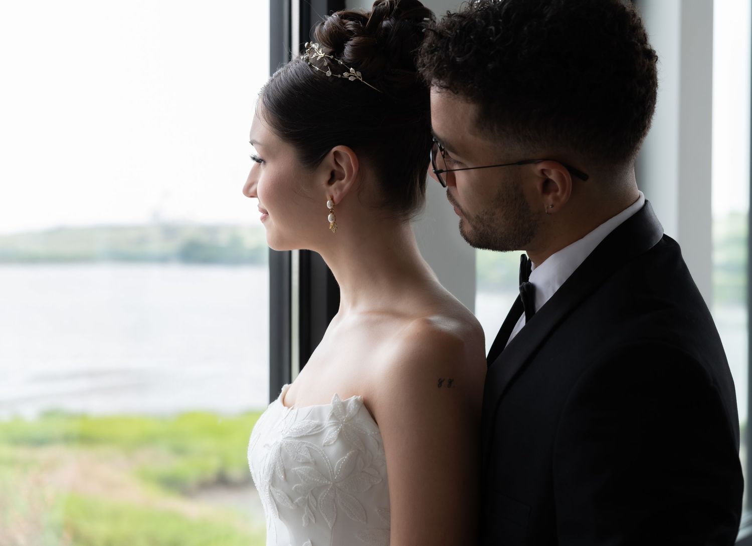A portrait of a bride and groom in natural light looking out a window in Bayonne, NJ