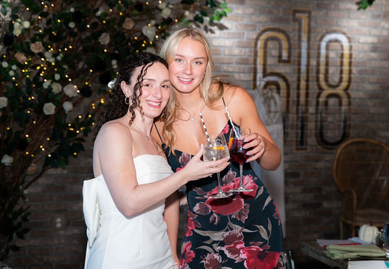Two women celebrating at a bridal shower in Freehold, NJ, holding drinks and toasting joyfully