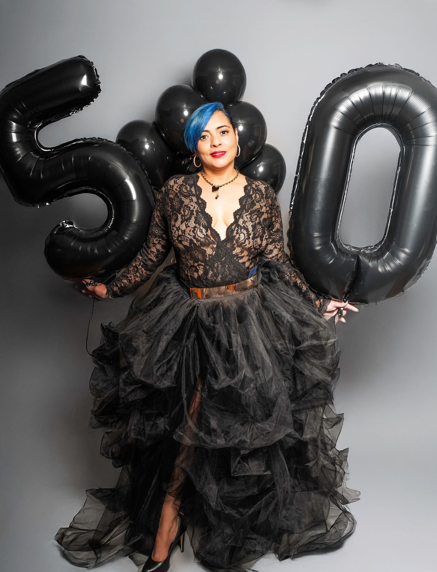 A portrait of a woman standing and holding ballons that say 50 for her 50th birthday photo shoot in Woodridge, NJ