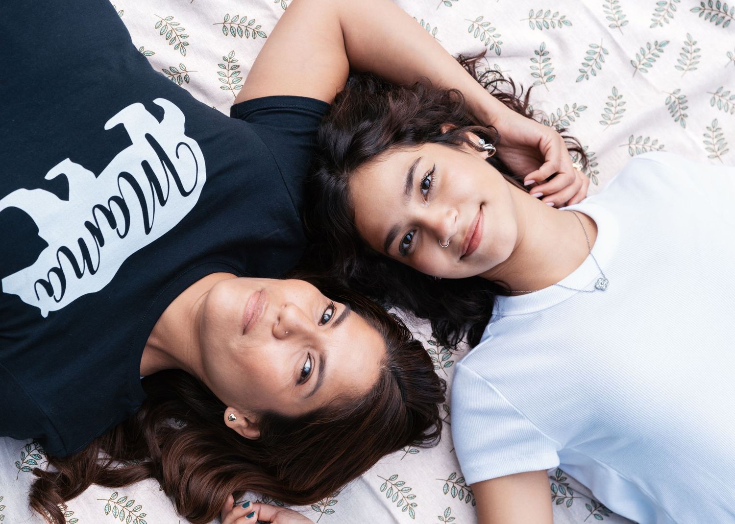 A mom is lying down with her daughter looking up at the camera during their family photoshoot in Nutley, NJ