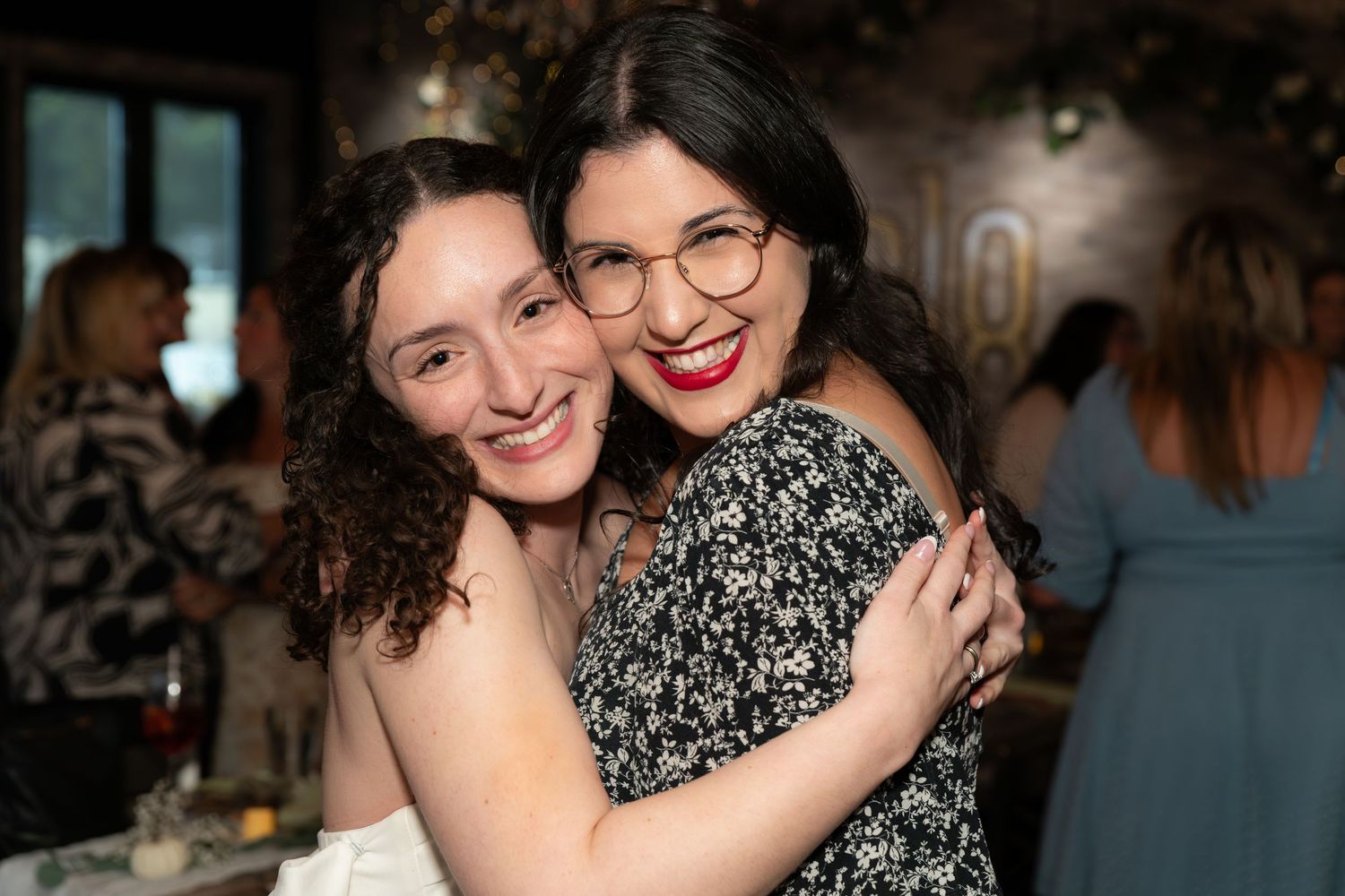 Two women posing together and hugging at a bridal shower celebration