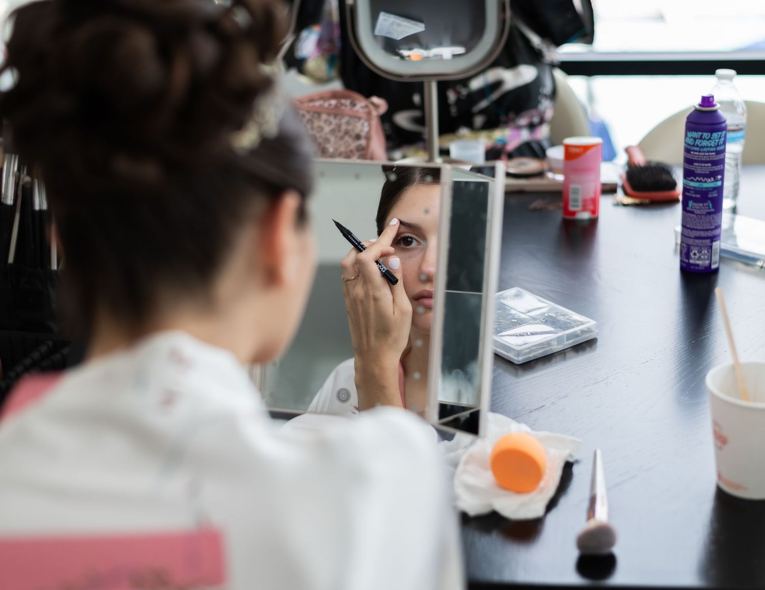 The bride is in her robe and is doing her makeup before she gets into her wedding dress in Bayonne, NJ