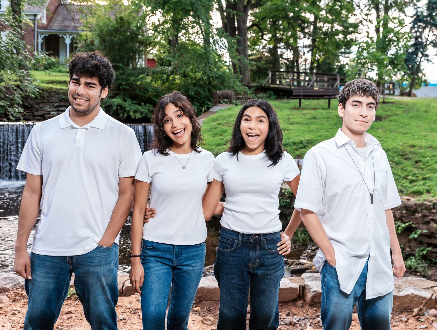 Four siblings pose for a portrait in the park as the sisters make funny faces during their family photo session in the park in Nutley, NJ