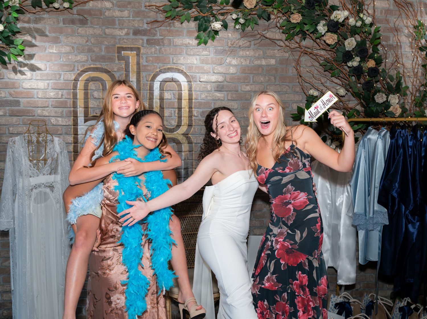Four women celebrating a bridal shower in Freehold, NJ, laughing and posing with funny props, capturing joyful, candid moments