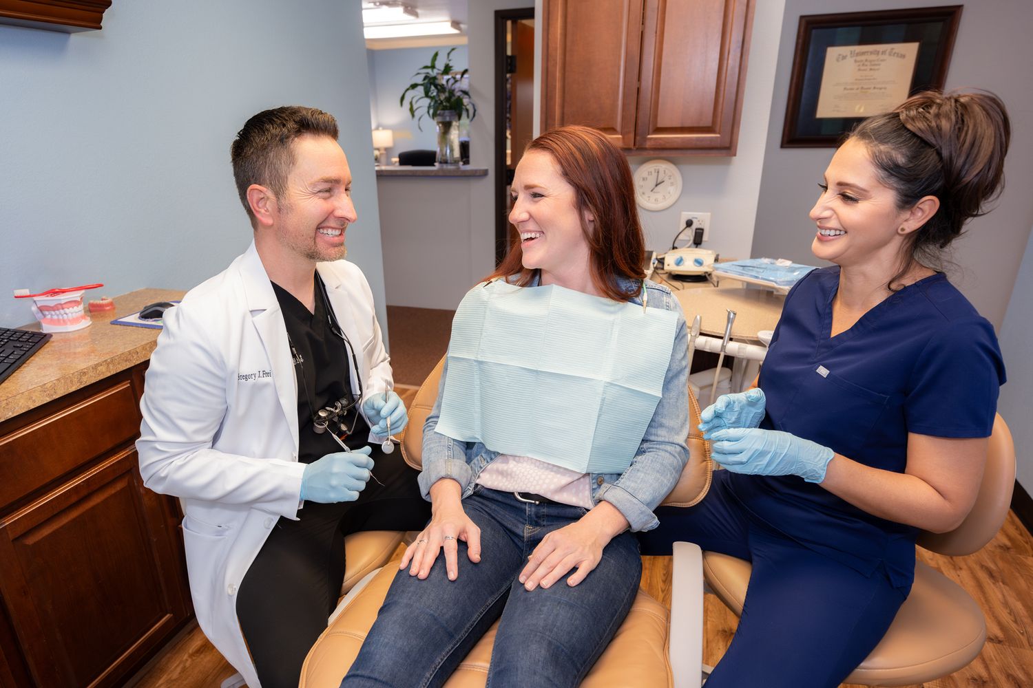 Dentist and dental hygienist smiling with happy patient during dental consultation in modern dental office.