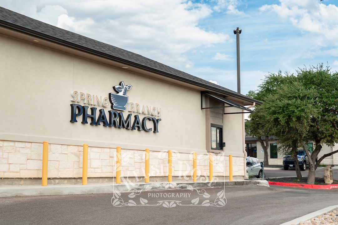 Front exterior of Spring Branch Pharmacy drive thru with driveway and window.
