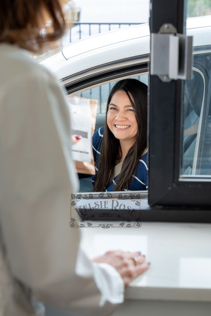 Smiling female customer in a car receiving service at a pharmacy drive-through window.