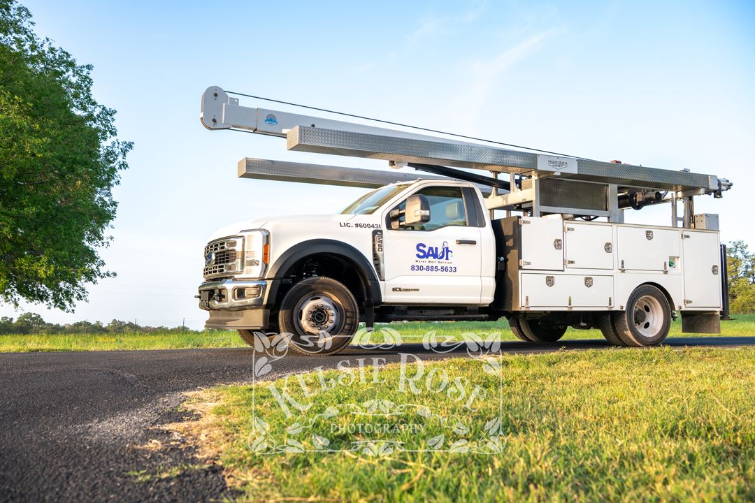 Saul Water Well Service white utility truck with boom parked on rural Texas road.