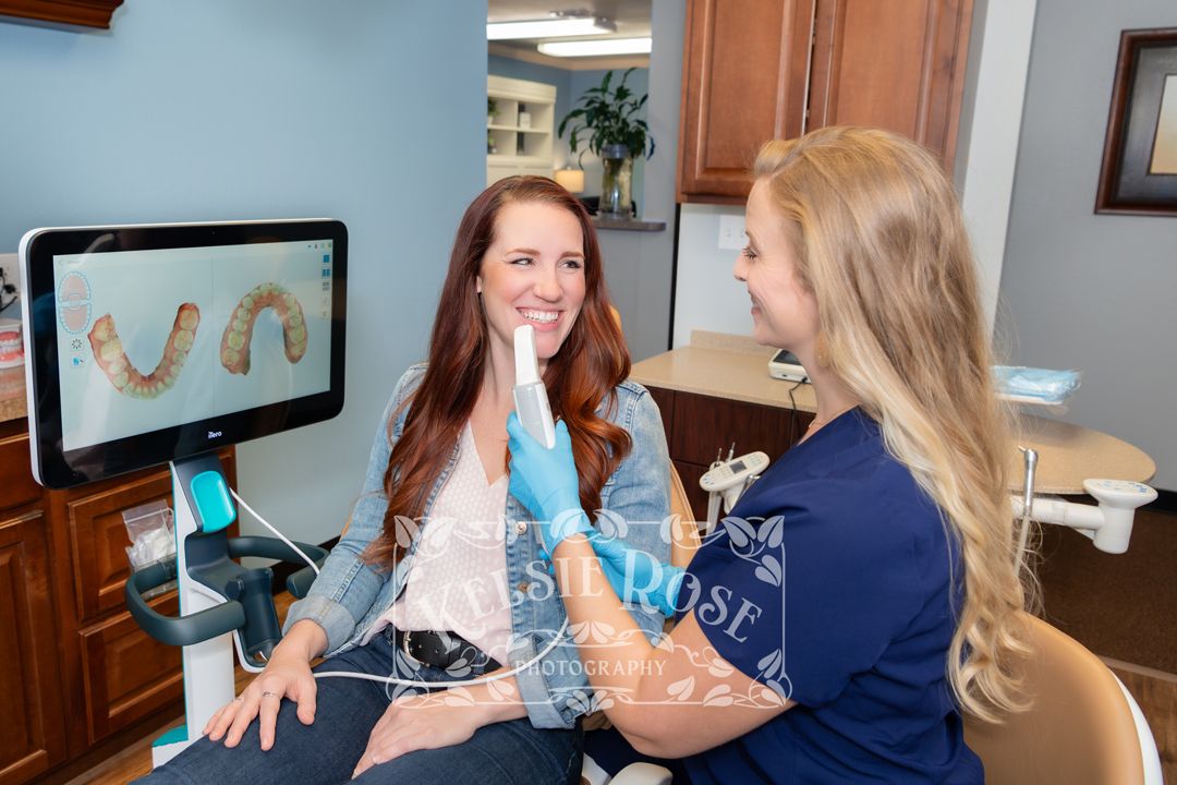 Dental hygienist showing patient 3D teeth scan on monitor during consultation.