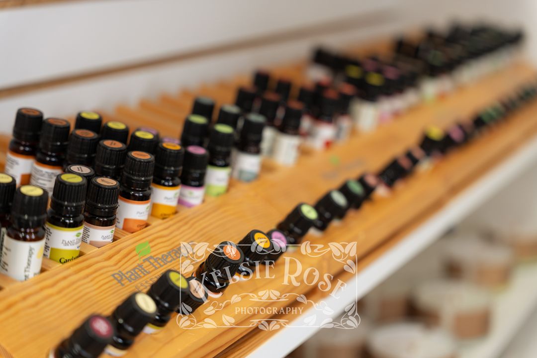 Close-up of rows of small essential oil bottles neatly arranged on a wooden display shelf in a pharmacy.