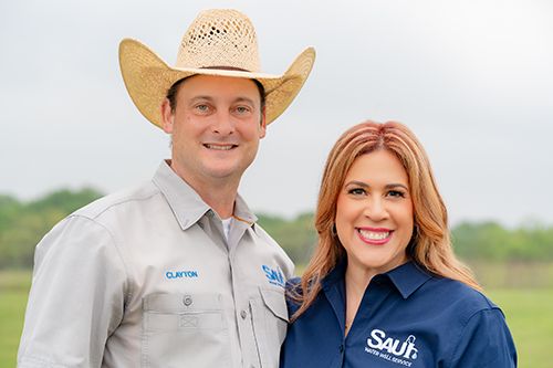 Headshot of smiling couple in branded uniforms posing together in an outdoor field.