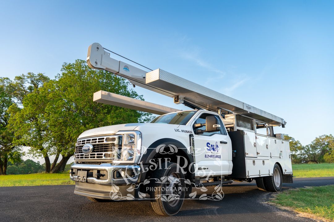 Saul Water Well Service heavy-duty white service truck with equipment boom on rural Texas road.