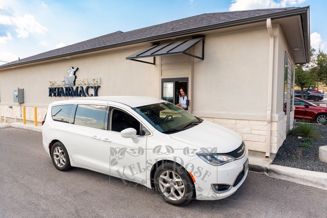 Exterior view of a pharmacy building with a white minivan at the drive-through lane.