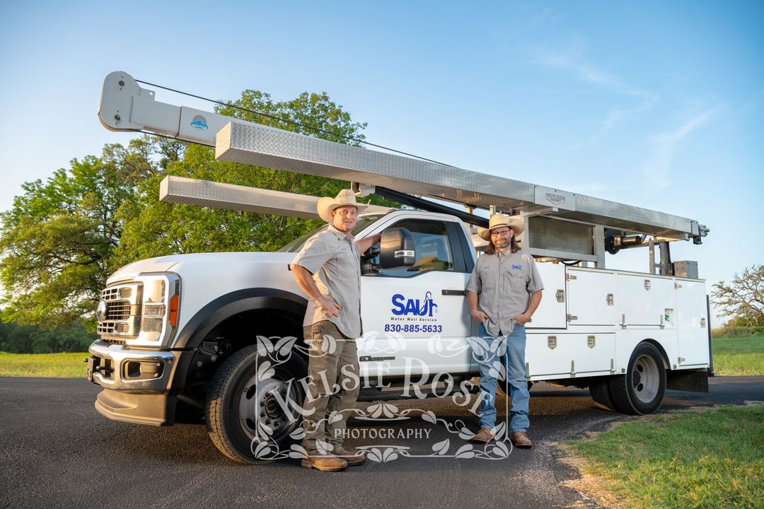 Two Saul Water Well Service workers in cowboy hats standing beside company service truck.