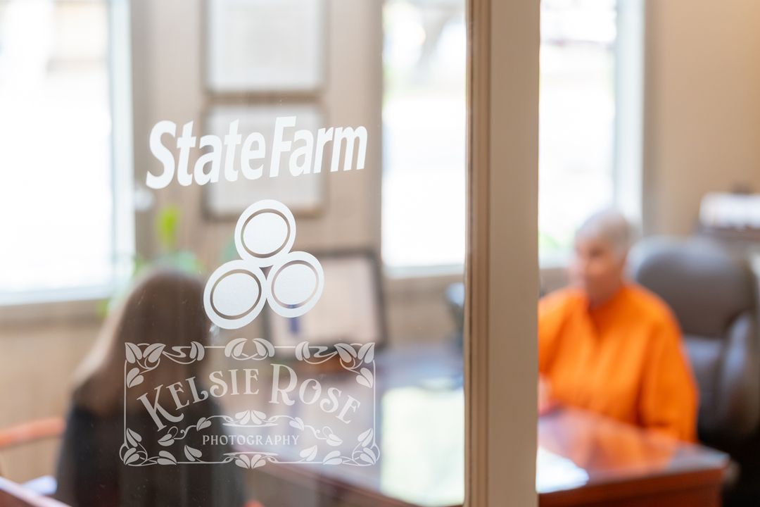 State Farm insurance office window with Kelsie Rose agent branding, two people visible in background.