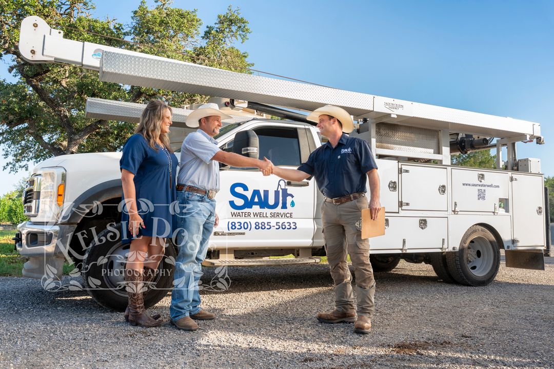 Business owner shaking hands with clients in front of a Saul Water Well Service truck outdoors in Texas.