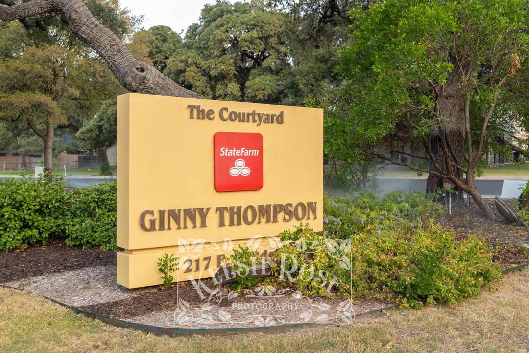 State Farm Ginny Thompson The Courtyard sign at 217, surrounded by lush greenery and colorful landscaping.
