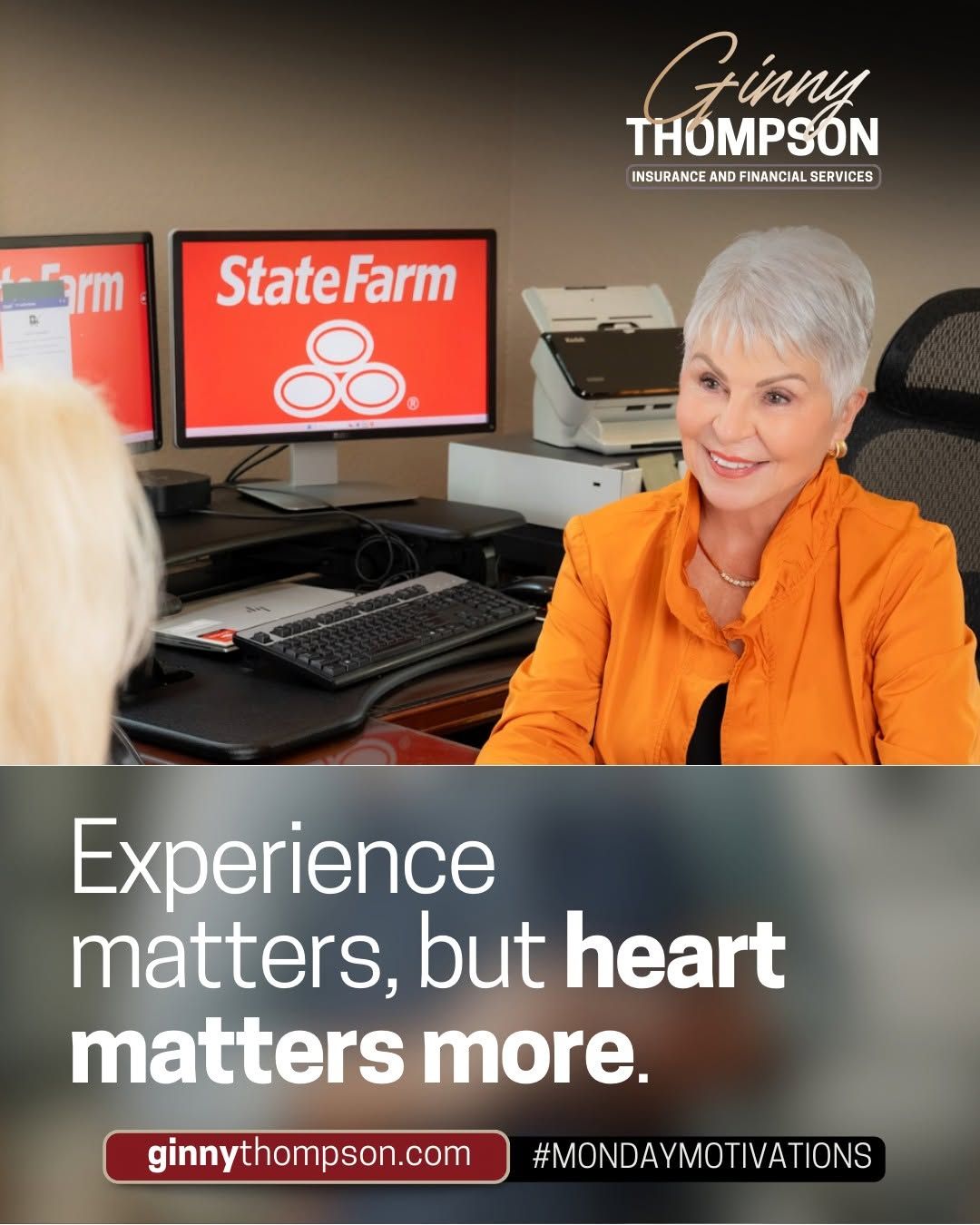 Ginny Thompson State Farm agent in orange jacket consulting with client at desk with dual monitors in office.