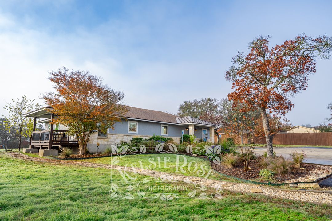 Exterior of charming ranch-style dental office surrounded by colorful autumn trees on a green lawn on an overcast day.