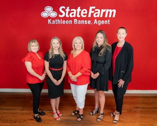 Five women in red and black outfits posing in front of a State Farm sign.