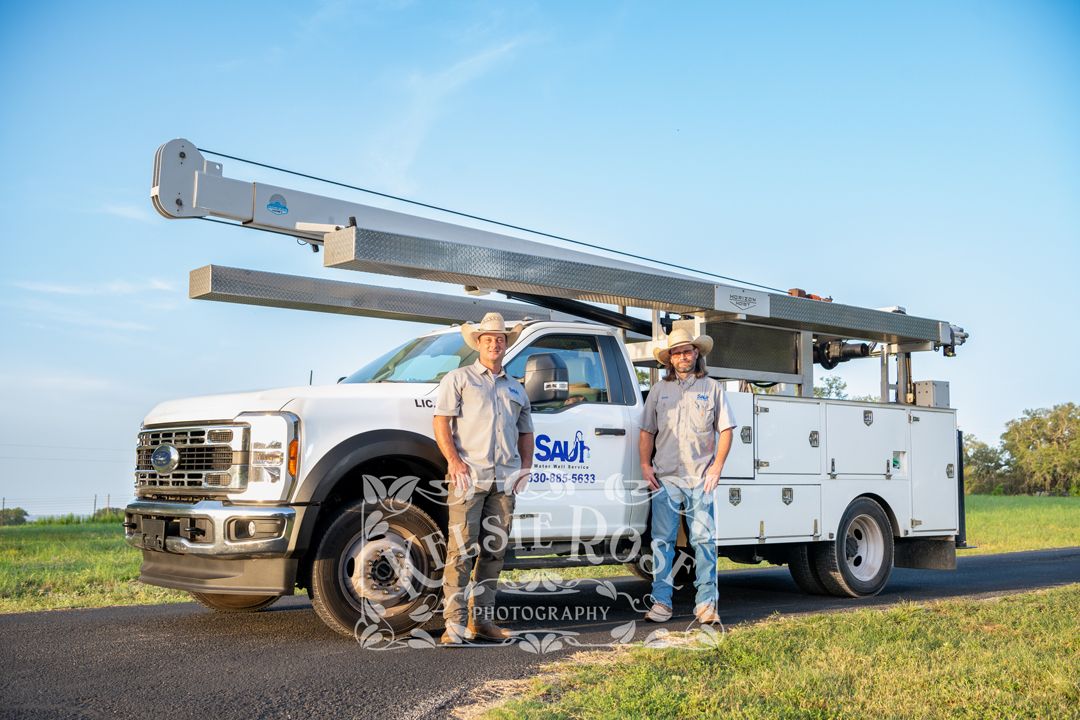 Two Saul Water Well Service workers in cowboy hats posing with large white service truck.