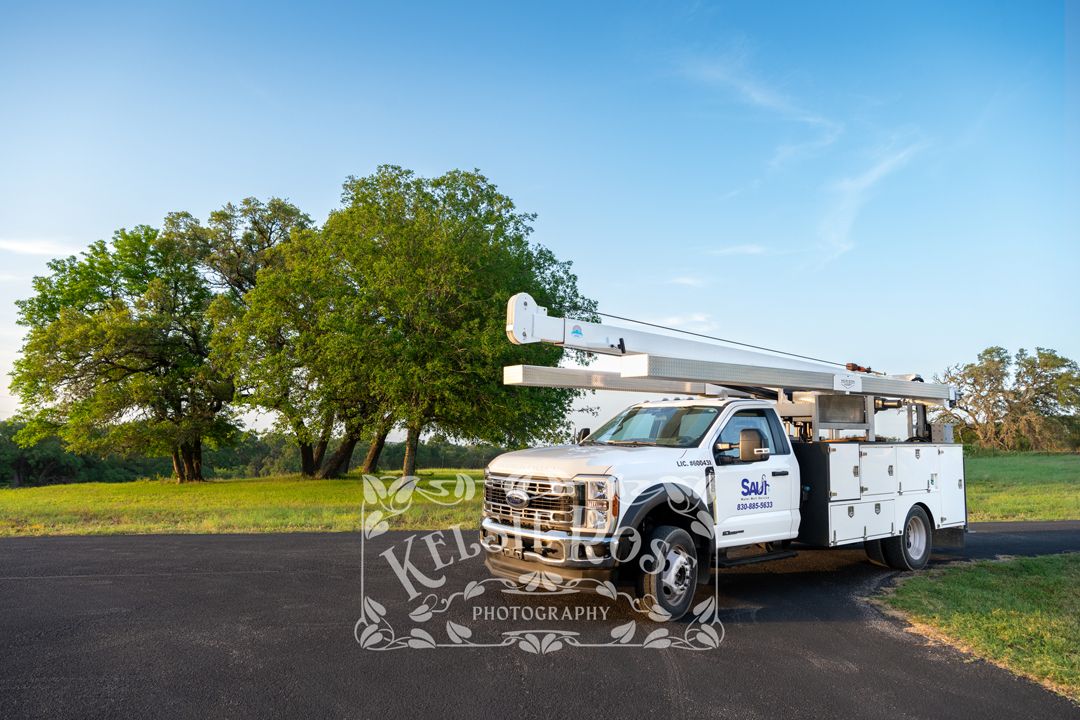 Saul Water Well Service white service truck parked on rural Texas road with green oak trees.