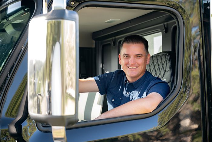 Smiling male businessman looking out of the window of a large commercial vehicle.