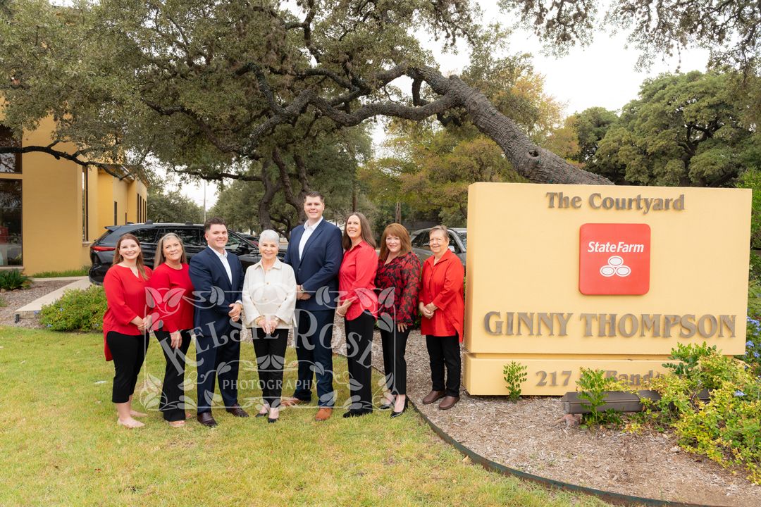 State Farm agent Ginny Thompson poses with her team outside The Courtyard office at 217, all wearing red and black attire.