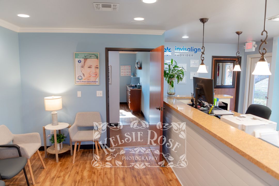 Dental office reception area with blue walls, wood counter, and Invisalign promotional display.