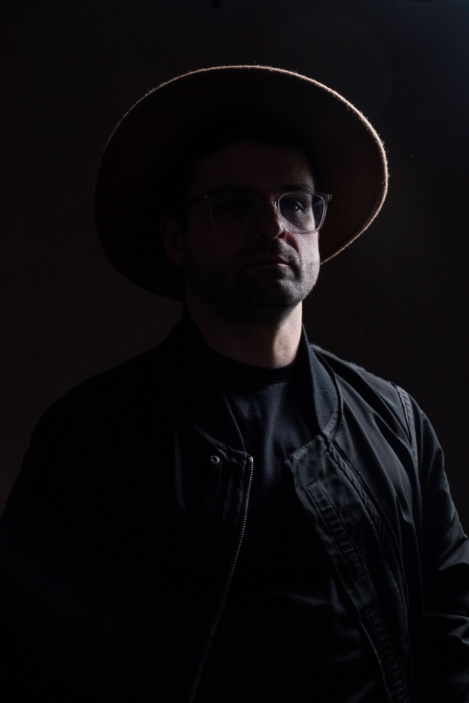 A dramatic noir-style portrait series showing a figure in shadow wearing a wide-brimmed hat against a dark background.