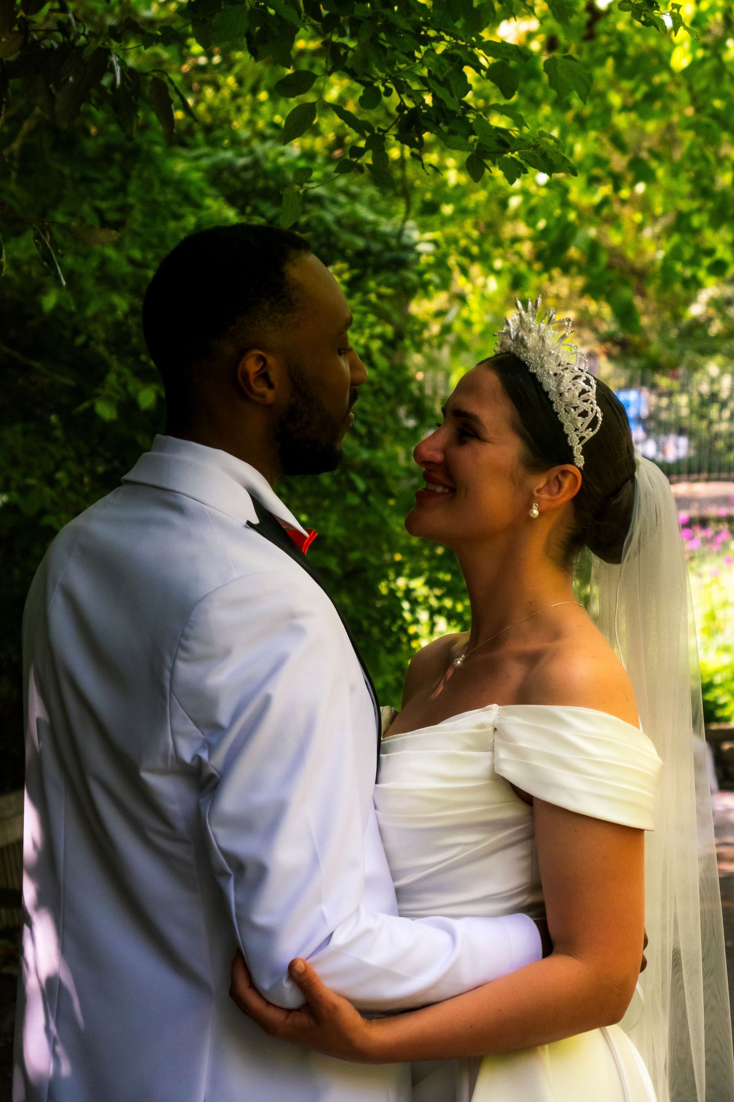 A couple shares an intimate moment in a garden setting on their wedding day.