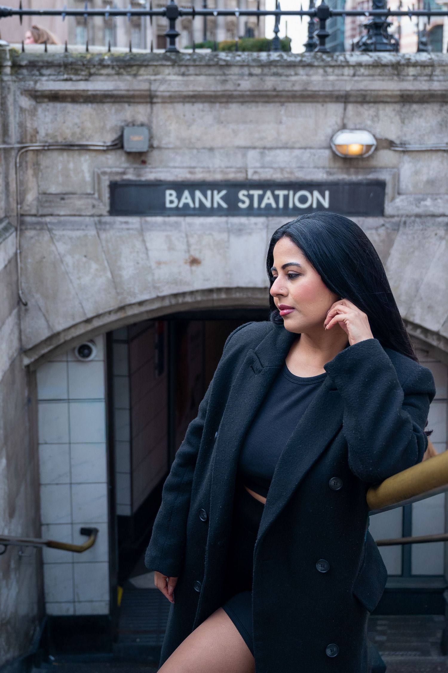 A series of black and white architectural photos showing a person in dark clothing posing near a Bank Station entrance.