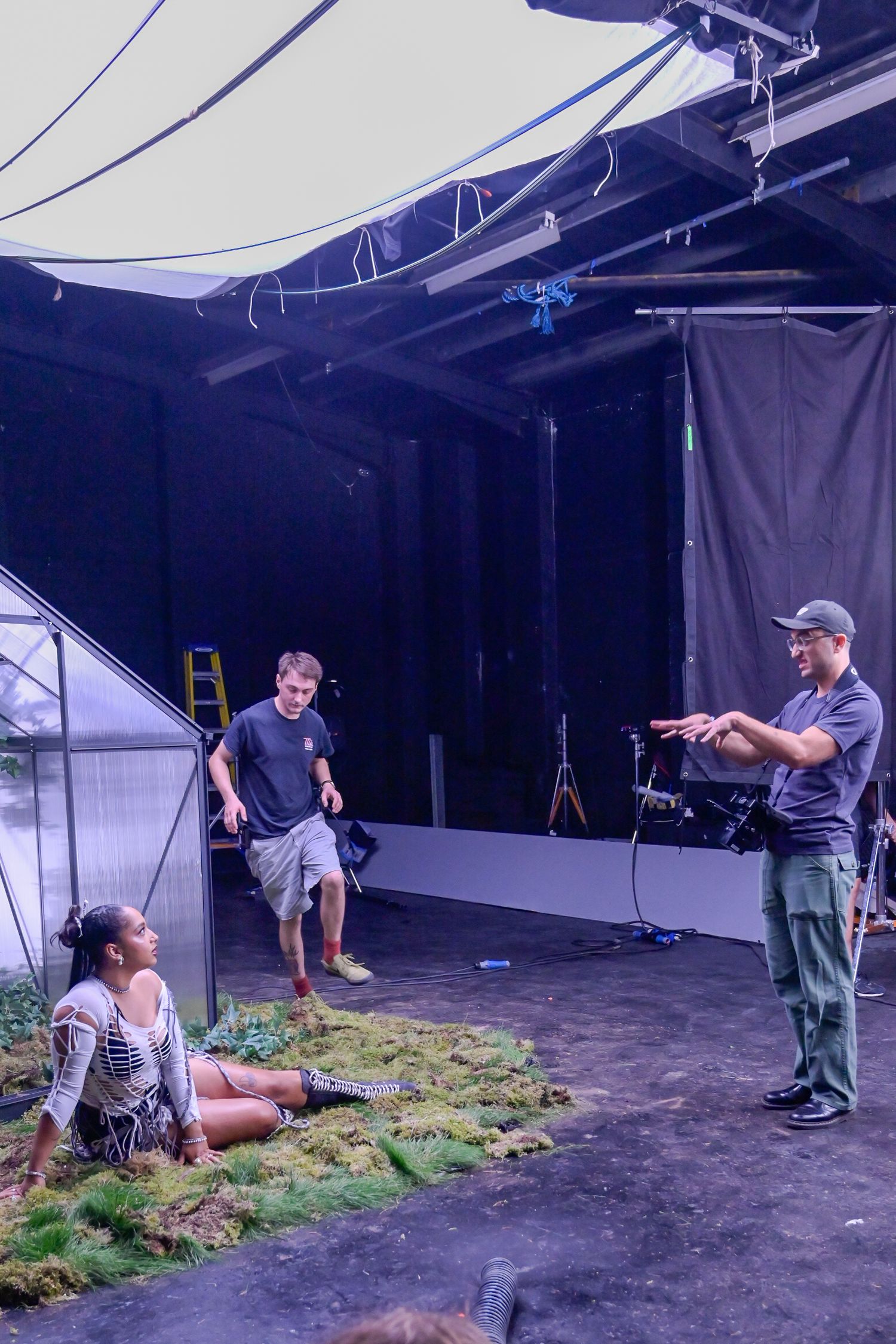 Behind-the-scenes photo shoot setup in a studio with lighting equipment and crew members.