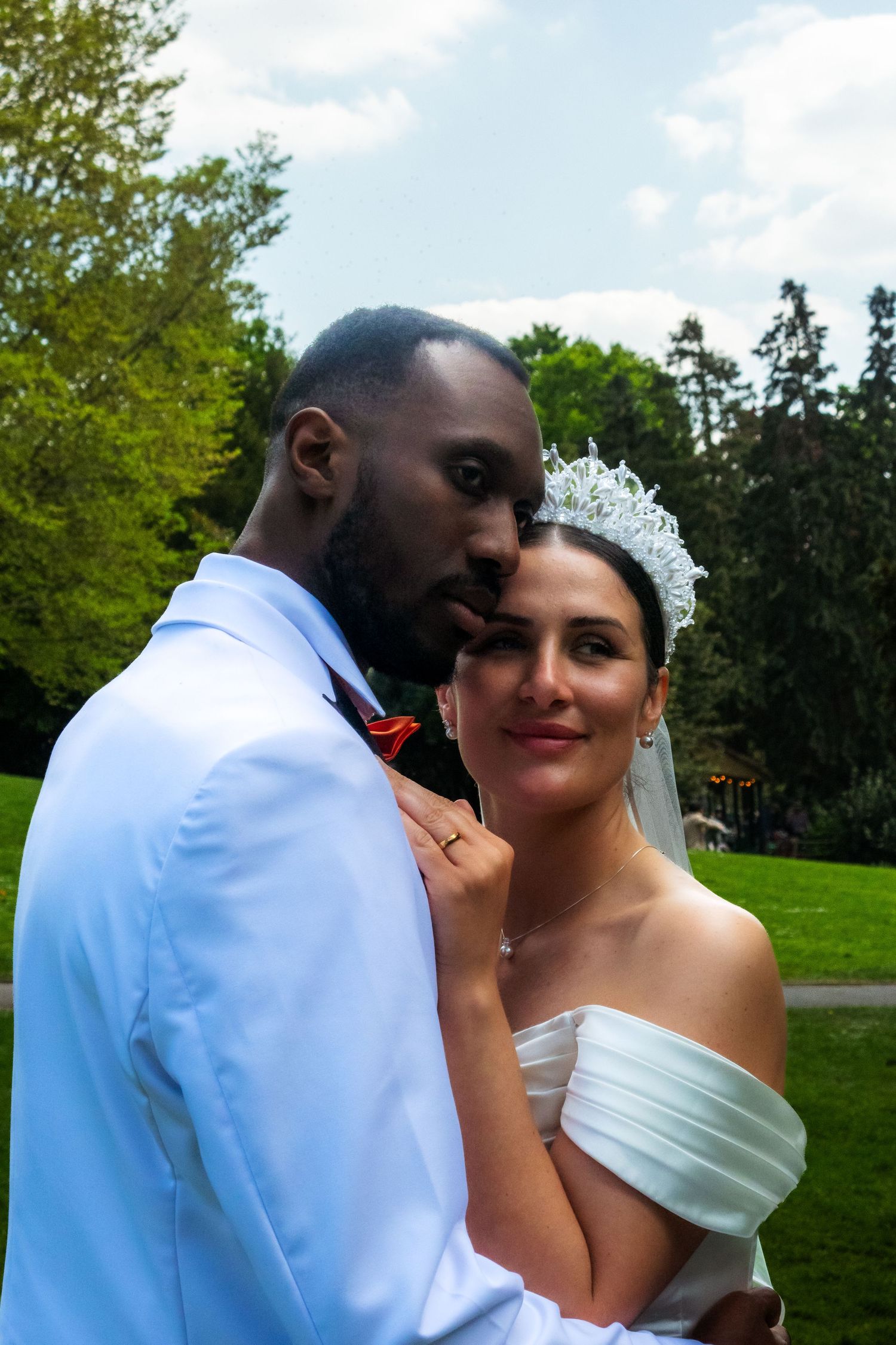 An intimate wedding portrait captures a tender moment between newlyweds in a park.