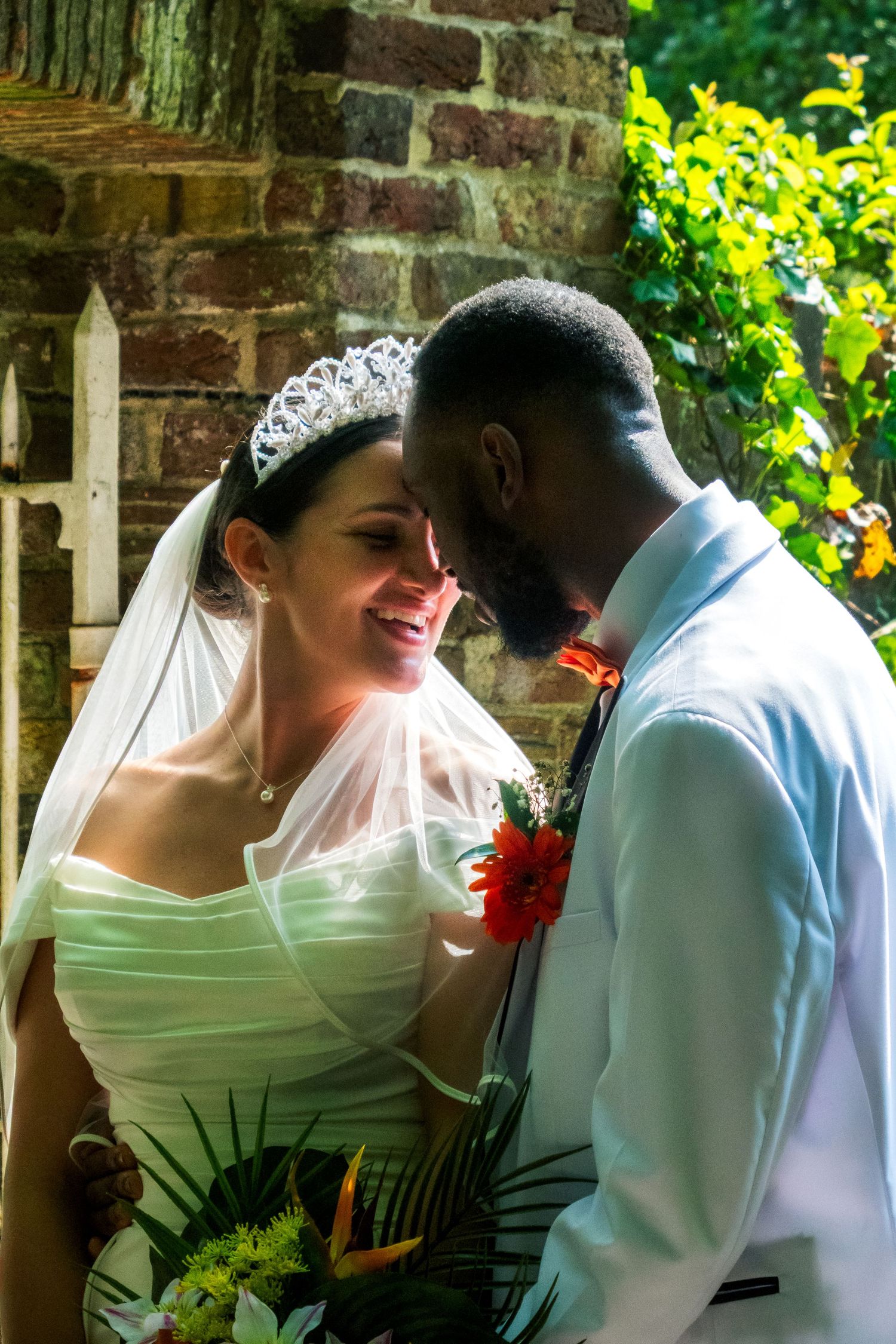 Romantic wedding photo sequence against brick wall and greenery backdrop.