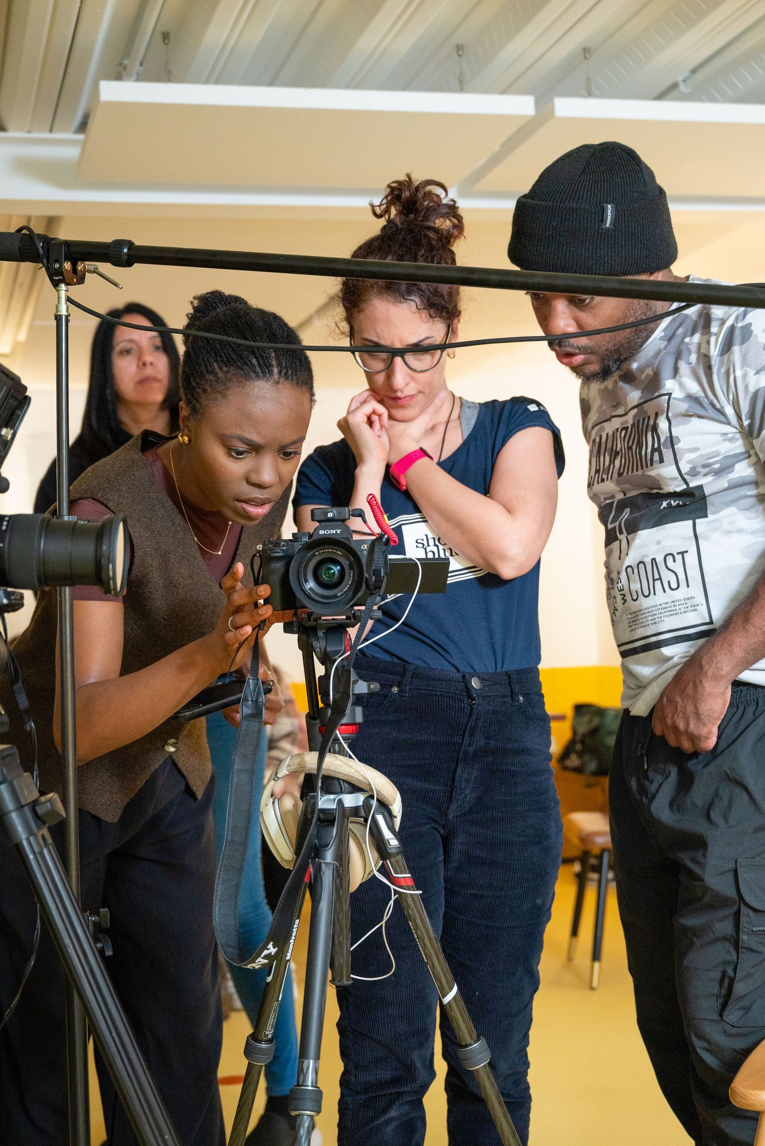 Film crew members work together to set up camera equipment and lighting on a professional video production set.