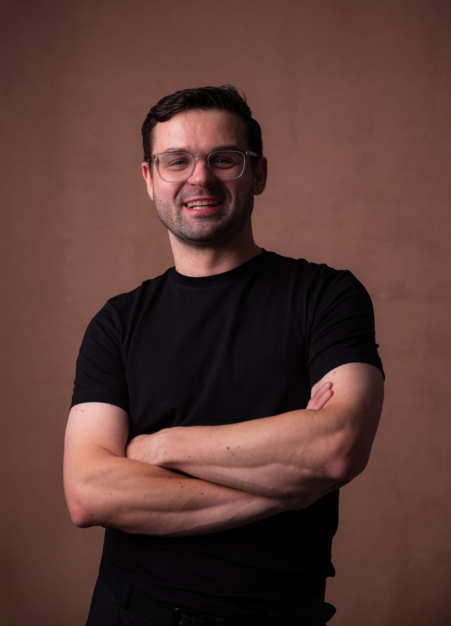 A sequence of portrait photos showing someone in a black t-shirt posing with crossed arms against a brown backdrop.