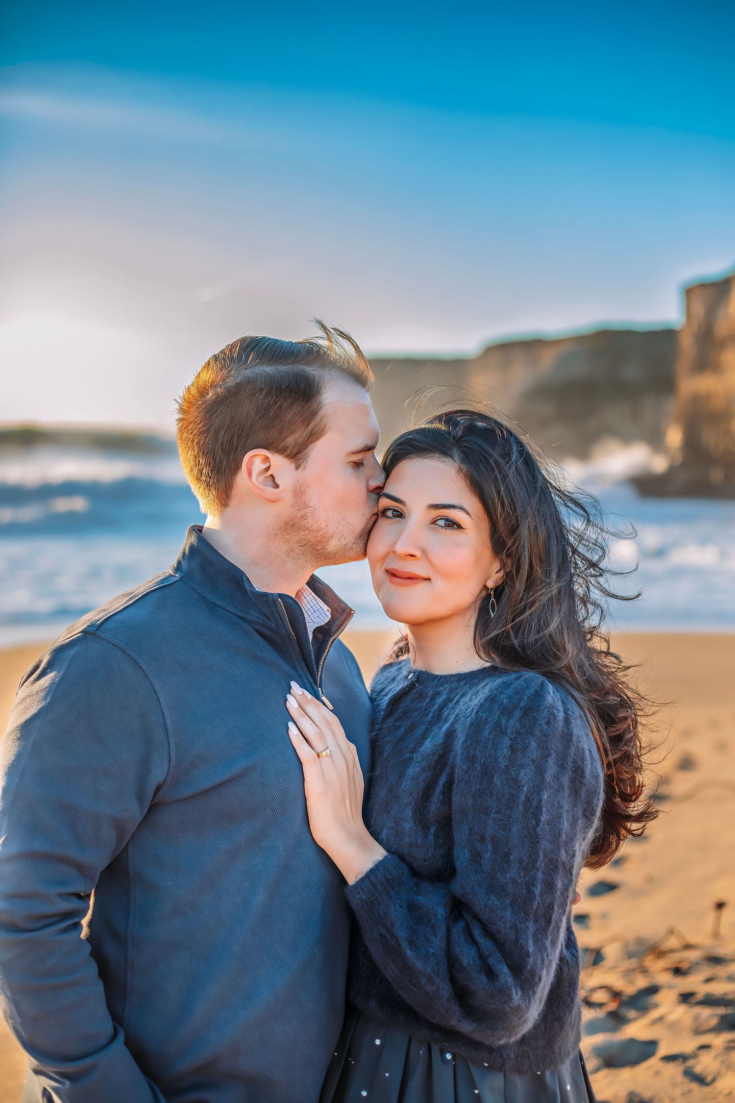 A couple kissing at a beach in Santa Cruz, CA lit with magical golden light